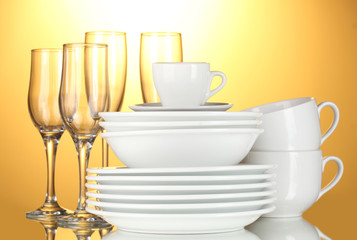 empty bowls, plates, cups and glasses on yellow background