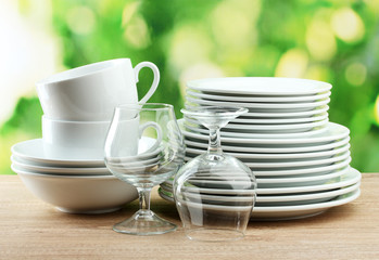 Clean dishes on wooden table on green background