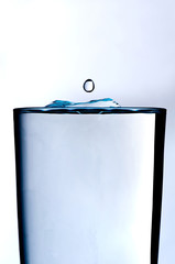 Wassertropfen fällt in ein Wasserglas