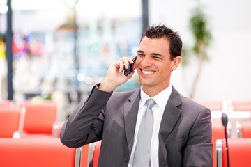 happy businessman talking on cell phone at airport