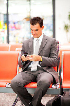young businessman sending text messages at airport