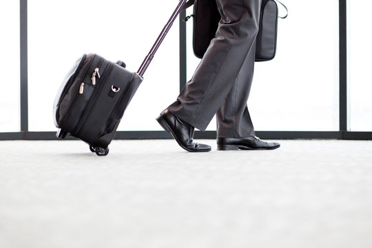 Businessman Walking In Airport With His Luggage