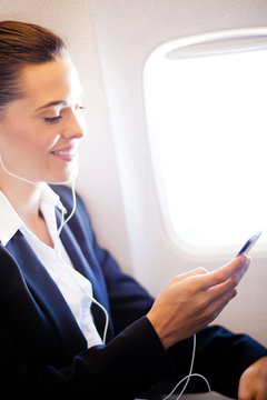 pretty businesswoman listening music on airplane
