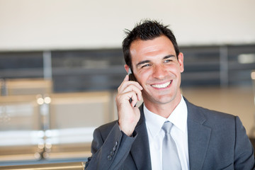 happy businessman talking on cell phone at airport