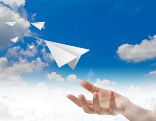 Hand throwing a paper plane in the sky