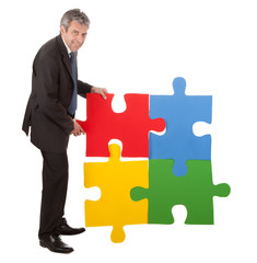 Senior businessman assembling a jigsaw puzzle