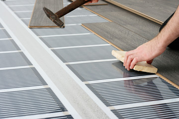 man installing laminate floor over infrared carbon heating syste - obrazy, fototapety, plakaty