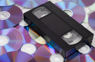 Naklejka premium CD vs VHS. VHS cassette lay on the many CD disks