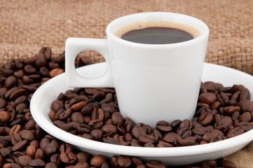 A cup of coffee on the background of coffee beans