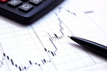 Ручка и калькулятор на графике фондовых торгов