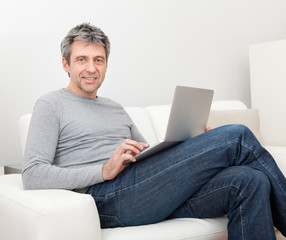 Senior man sitting in sofa and using laptop