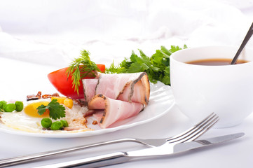 Bacon with fried eggs and tomatoes, a peas and corn