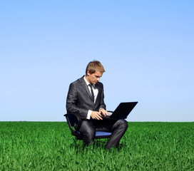 Businessman sitting outdoors with laptop computer