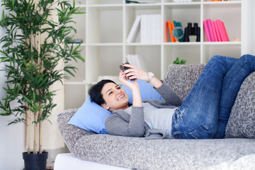 Young girl reading an SMS while relaxing on sofa