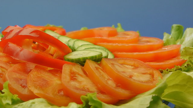 Sliced vegetables with lettuce on blue background