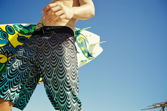male surfer walking with surfboard on the beach sunny day