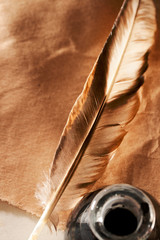 Feather and ink bottle on paper background