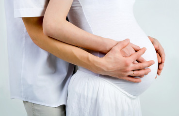 Mom and Dad with hands on the baby, on gray background