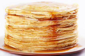 A stack of thin pancakes with honey