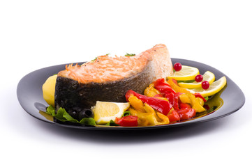 Fried salmon with grilled vegetable on a black plate