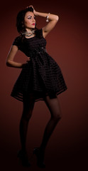 Fototapeta na wymiar Beautiful young woman in dress on dark background.
