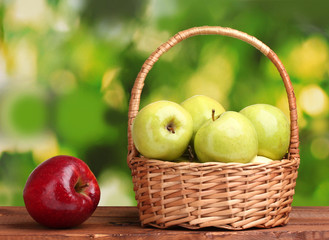 juicy green apples in basket and red apple