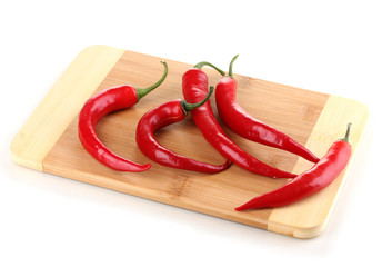 Red hot chili peppers on wooden plank isolated on white