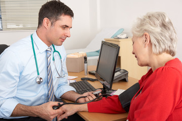 British doctor taking senior woman's blood pressure