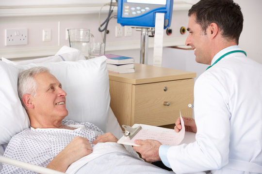 Doctor With Senior Male Patient On USA Hospital Ward