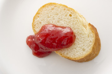 cut baguettes and strawberry jam on white background