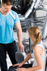 Personal trainer with young woman at gym