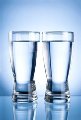 Two glasses of water on a blue background