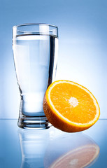 Glass of water and orange on a blue background
