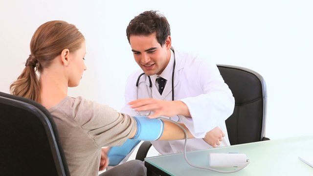 A doctor checking his patient blood pressure