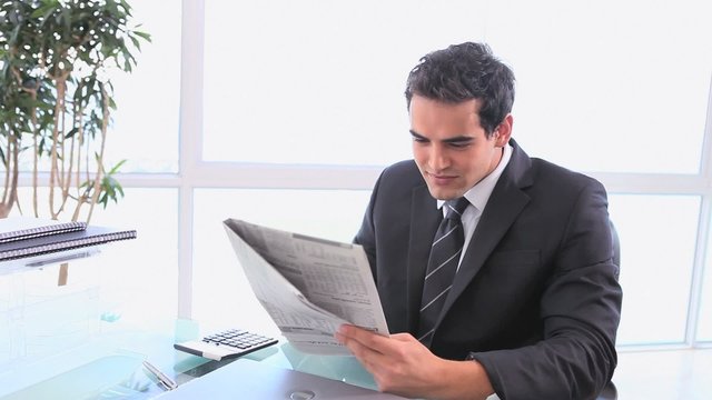 Man turning off his computer to reading the newspaper
