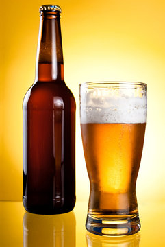 One glass and Bottle of fresh light beer on yellow background