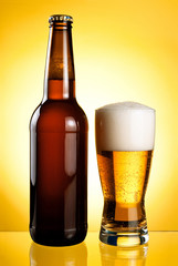 One glass and Bottle of fresh light beer on yellow background