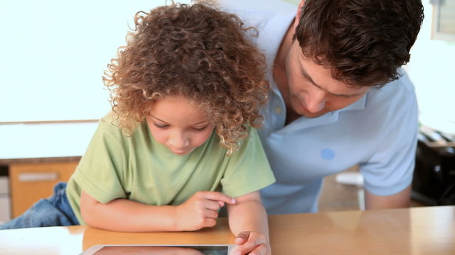 Boy using a tablet computer with his father
