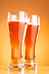 Two glass of beer over yellow background