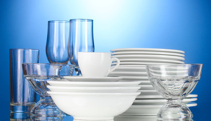 empty bowls, plates, cups and glasses on blue background