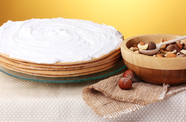 cake on glass stand and nuts on table on yellow background