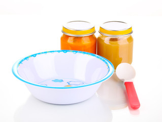 Jars of baby puree with plate and spoon isolated on white