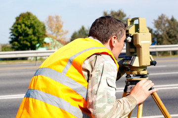 Surveyor engineer making measuring at highway by theodolite