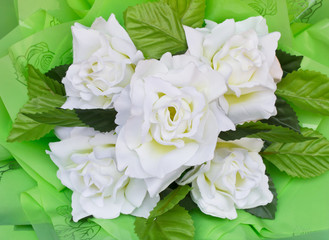 Artificial flowers made from white plastic with green leaves.