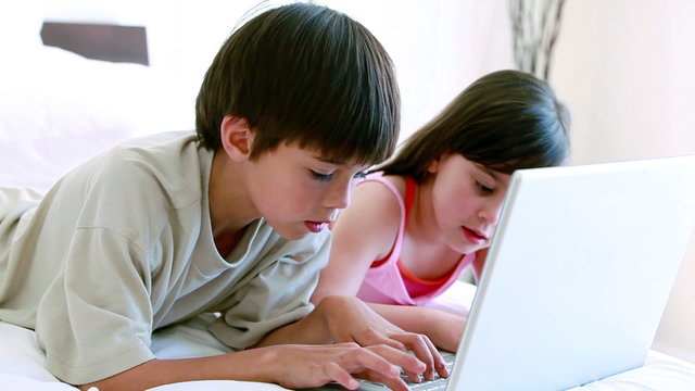 Siblings typing on a laptop