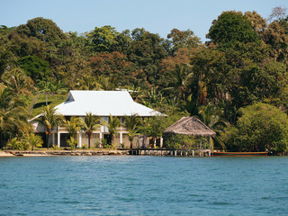 Waterfront Caribbean house with a tropical hut over water and jungle in background, Bocas del Toro, Panama, Central America