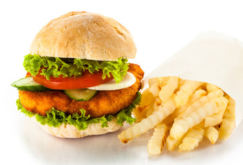 Big hamburger, French fries and vegetables on white background