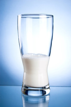 Half glass of milk on a blue background