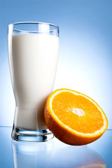 Fresh Glass of Milk and Half of juicy orange on a blue backgroun