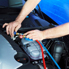 Motor mechanic works on engine bay with air handling unit